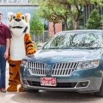 Dave and Carol Mansen and LeeRoy the Tiger pose by their car in front of CSI